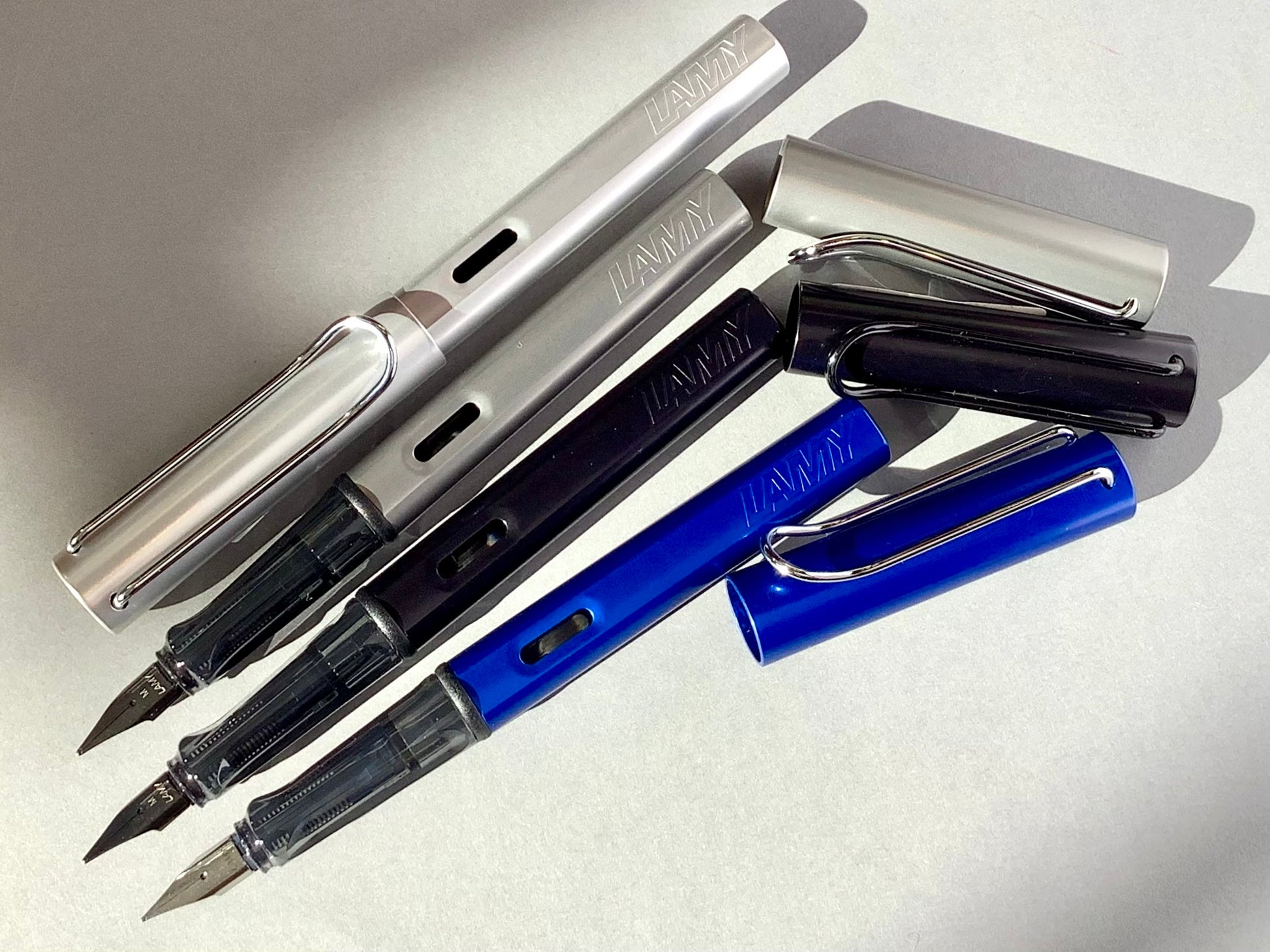 Füllhalter von LAMY aus Aluminium in blau, schwarz und silber (Griffstück aus transparentem Kunststoff). 
Erhältlich bei Polly Paper Schreibwaren in Berlin-Mitte
