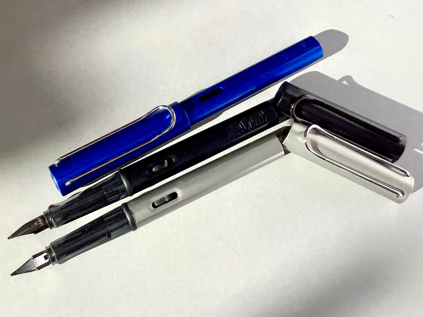 Füllhalter von LAMY aus Aluminium in blau, schwarz und silber (Griffstück aus transparentem Kunststoff). 
Erhältlich bei Polly Paper Schreibwaren in Berlin-Mitte