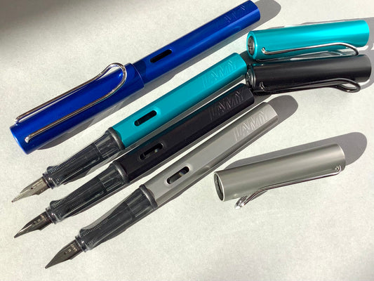 Füllhalter von LAMY aus Aluminium in blau, schwarz, silber oder türkis (Griffstück aus transparentem Kunststoff). 
Erhältlich bei Polly Paper Schreibwaren in Berlin-Mitte