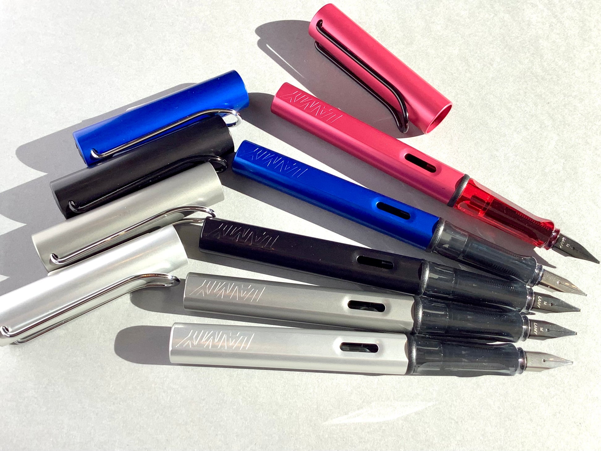 Füllhalter von LAMY aus Aluminium in blau, schwarz, silber und rot (Griffstück aus transparentem Kunststoff). 
Erhältlich bei Polly Paper Schreibwaren in Berlin-Mitte