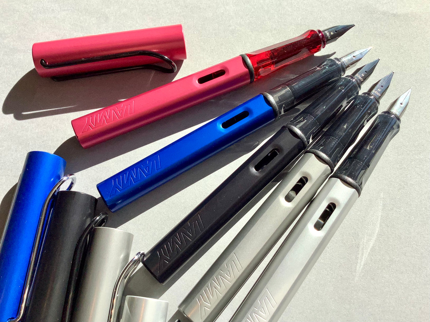 Füllhalter von LAMY aus Aluminium in blau, schwarz, silber oder rot (Griffstück aus transparentem Kunststoff). 
Erhältlich bei Polly Paper Schreibwaren in Berlin-Mitte