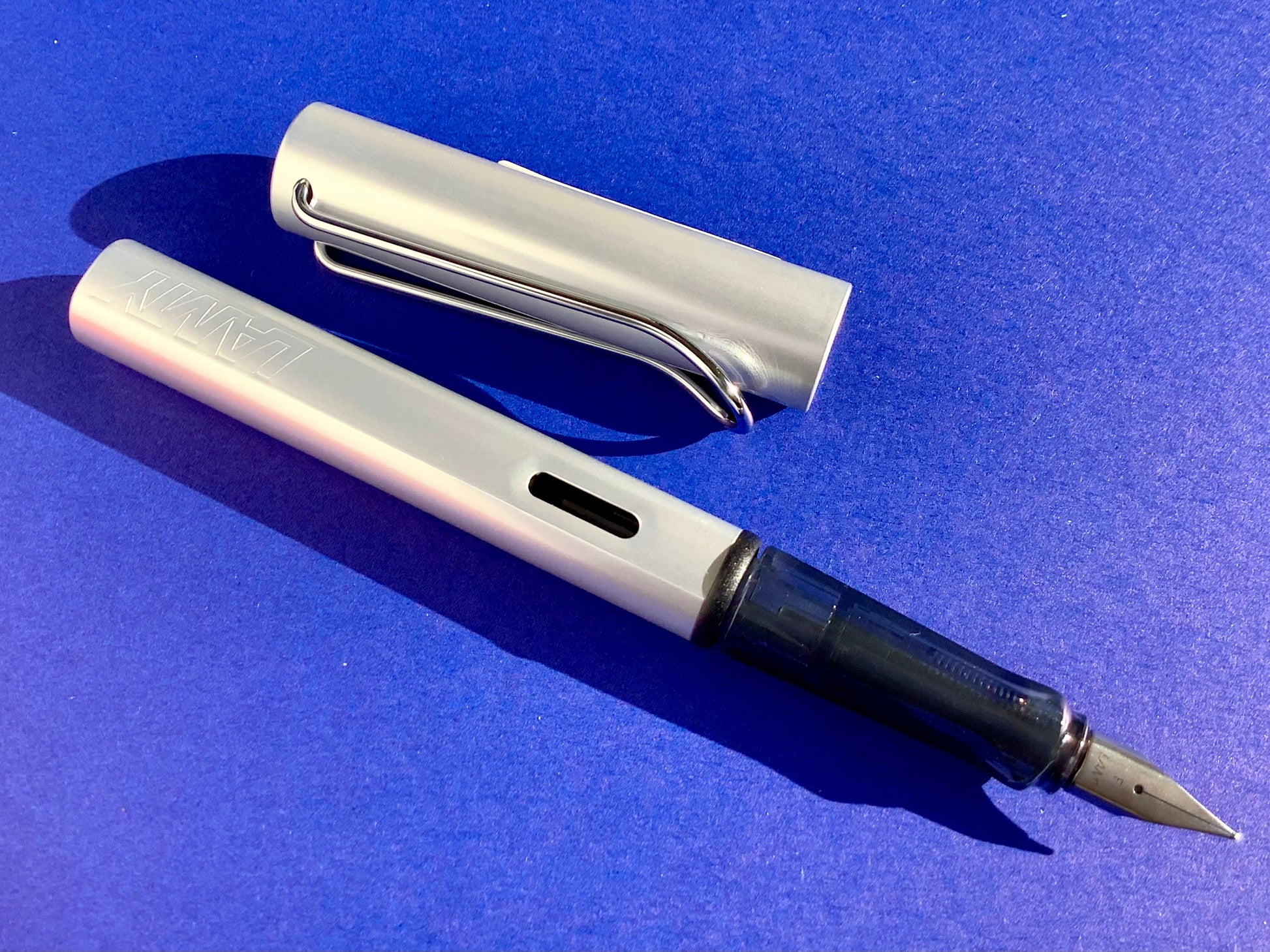 Füllhalter von LAMY aus Aluminium in whitesilver (Griffstück aus schwarz-transparentem Kunststoff). 
Erhältlich bei Polly Paper Schreibwaren in Berlin-Mitte