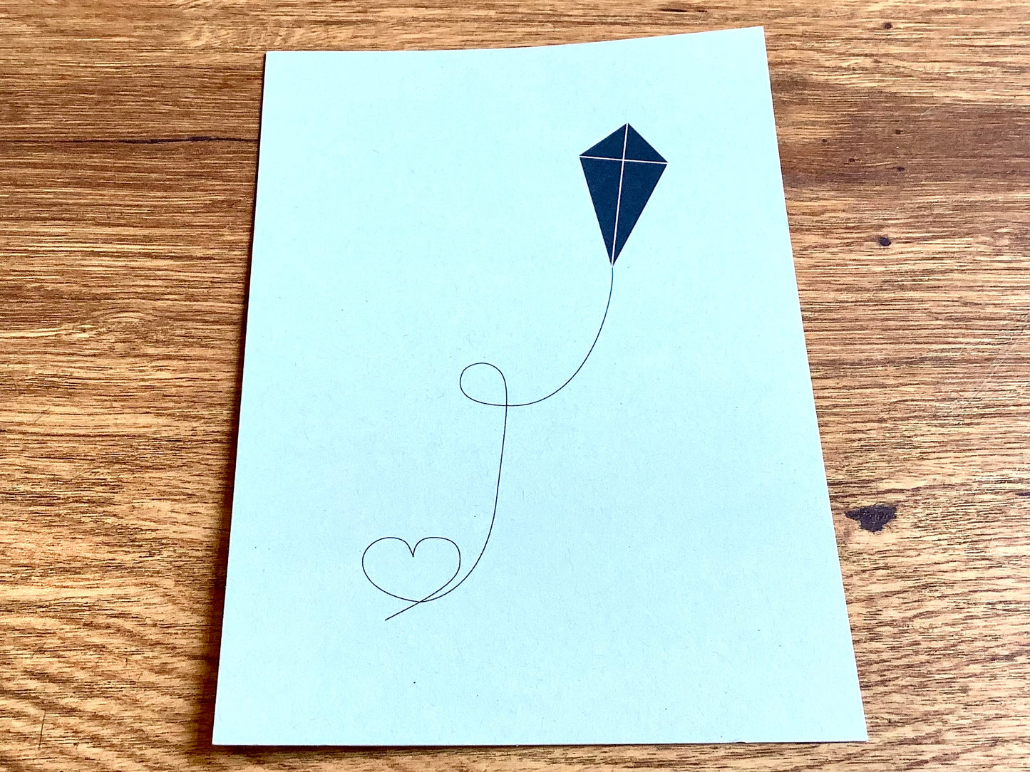 Dunkelblauer Drachen, dessen Schnur ein Herz formt auf mintfarbenem Hintergrund
- Postkarte aus Recyclingkarton von Papier ahoi aus Hamburg