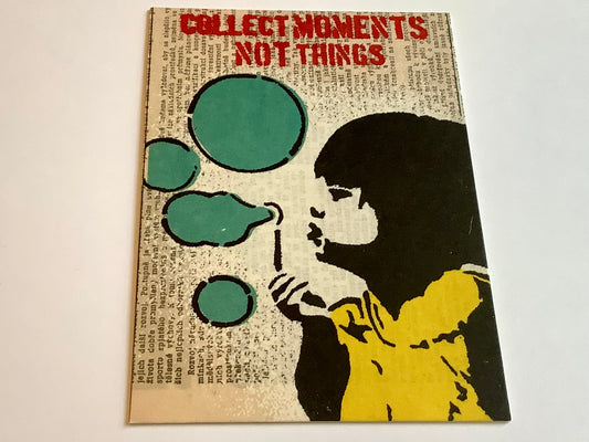 Auf der illustriertern Postkarte sieht man ein Mädchen mit Seifenblasen im Graffiti-Schablonenstil von Banksy. Darüber der Satz "Collect moments not things"