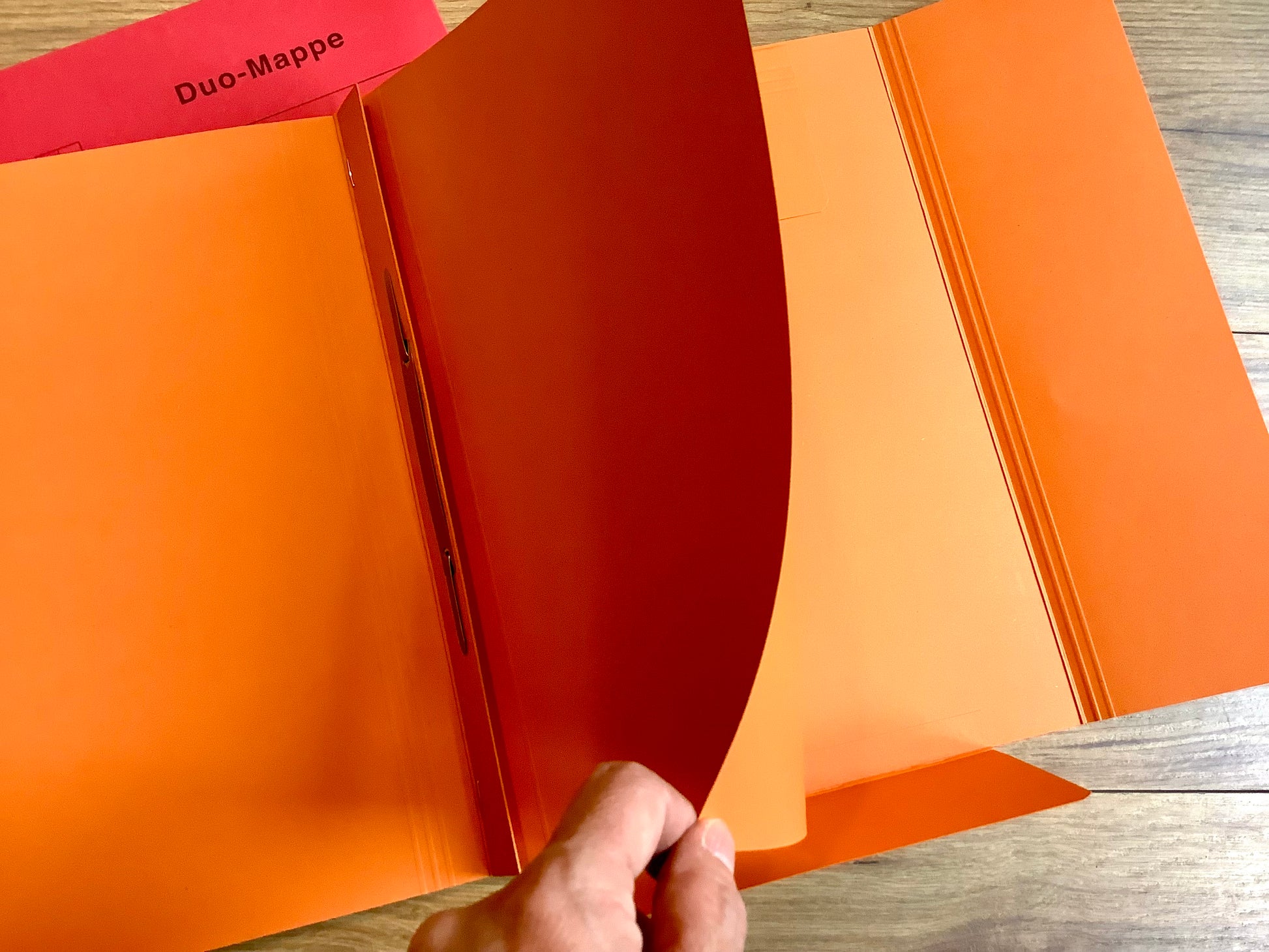 Praktische Kombi: ein Schnellhefter, der hinten daran noch eine Einschlagmappe hat. Orange.