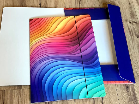 In grafischen Wellen in Regenbogenfarben bedruckte Sammelmappe mit Gummizug aus Recyclingpappe. 
Erhältlich  bei Polly Paper - umweltfreundlicher Schulbedarf in Berlin-Mitte