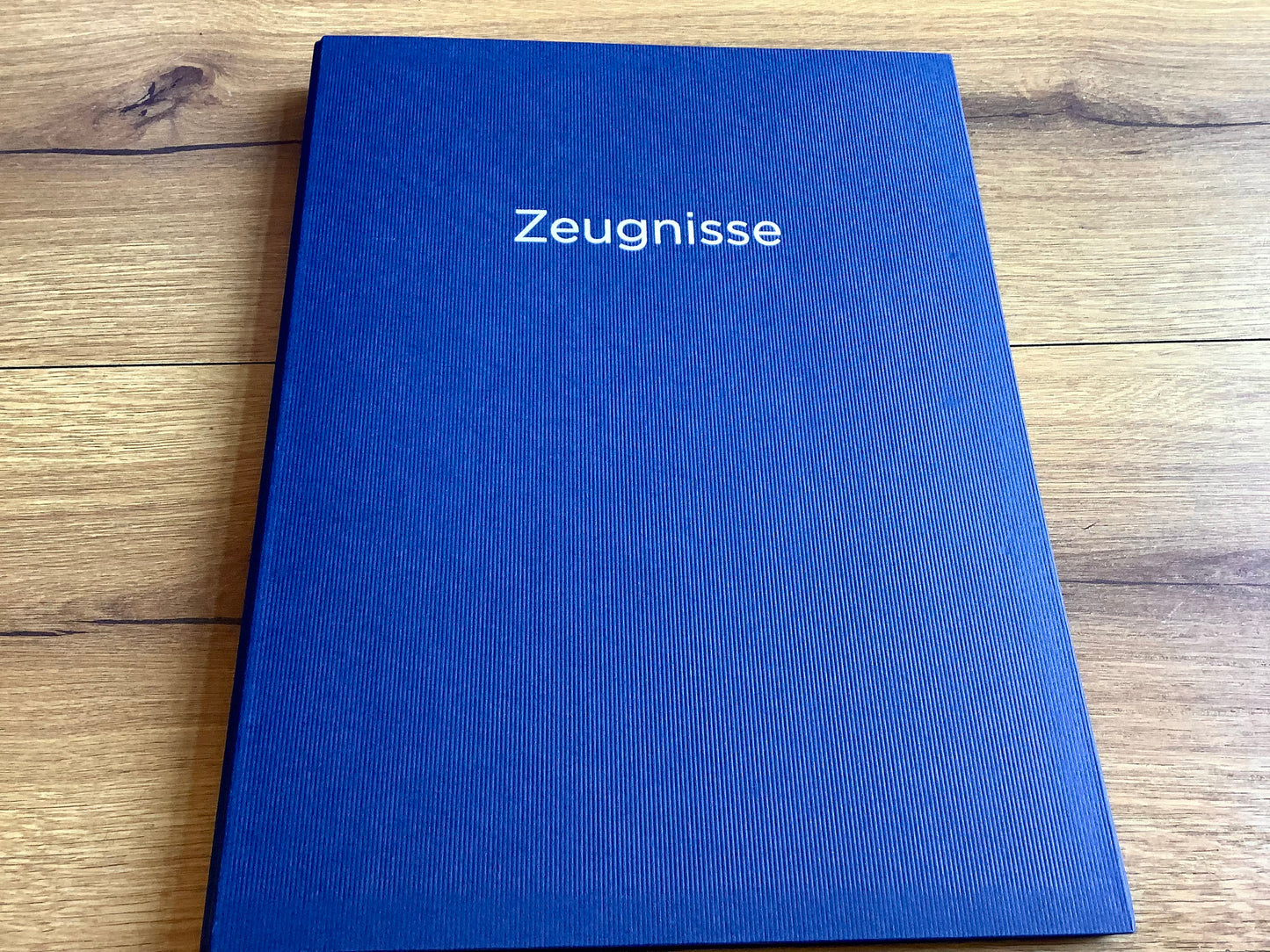 Blaue Zeugnismappe mit silbernem Aufdruck "Zeugnisse" .
Diese Mappe und anderen Schulbedarf finden Sie bei Polly Paper in Berlin-Mitte