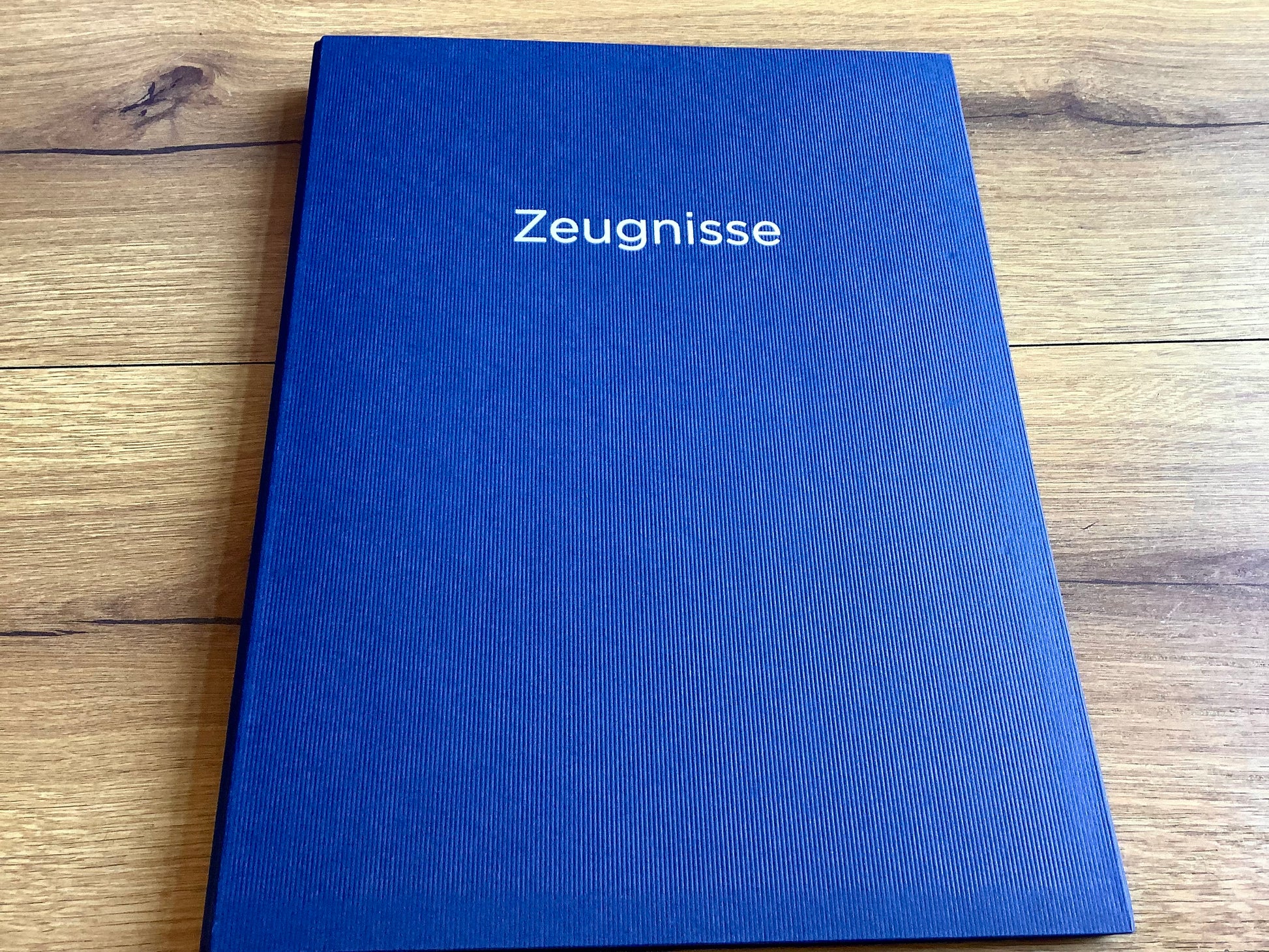 Blaue Zeugnismappe mit silbernem Aufdruck "Zeugnisse" .
Diese Mappe und anderen Schulbedarf finden Sie bei Polly Paper in Berlin-Mitte