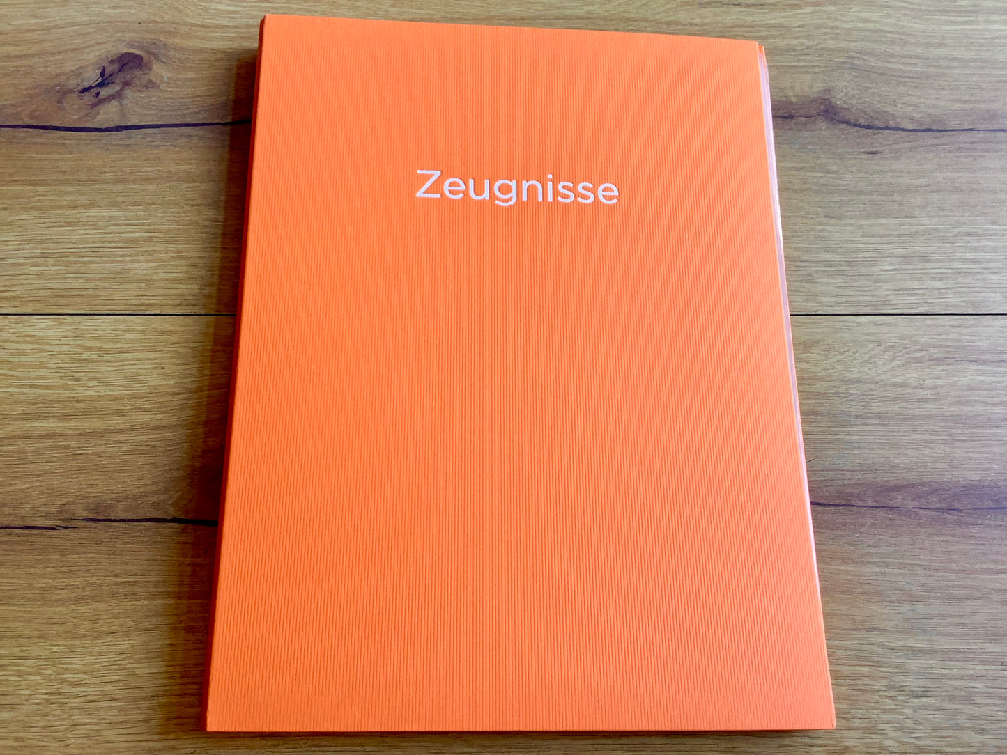 Orangefarbene Zeugnismappe mit silbernem Aufdruck "Zeugnisse" .
Diese Mappe und anderen Schulbedarf finden Sie bei Polly Paper in Berlin-Mitte