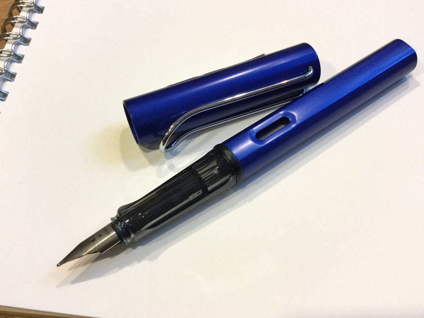 Füllhalter von LAMY aus Aluminium in blau (Griffstück aus schwarz-transparentem Kunststoff). 
Erhältlich bei Polly Paper Schreibwaren in Berlin-Mitte
