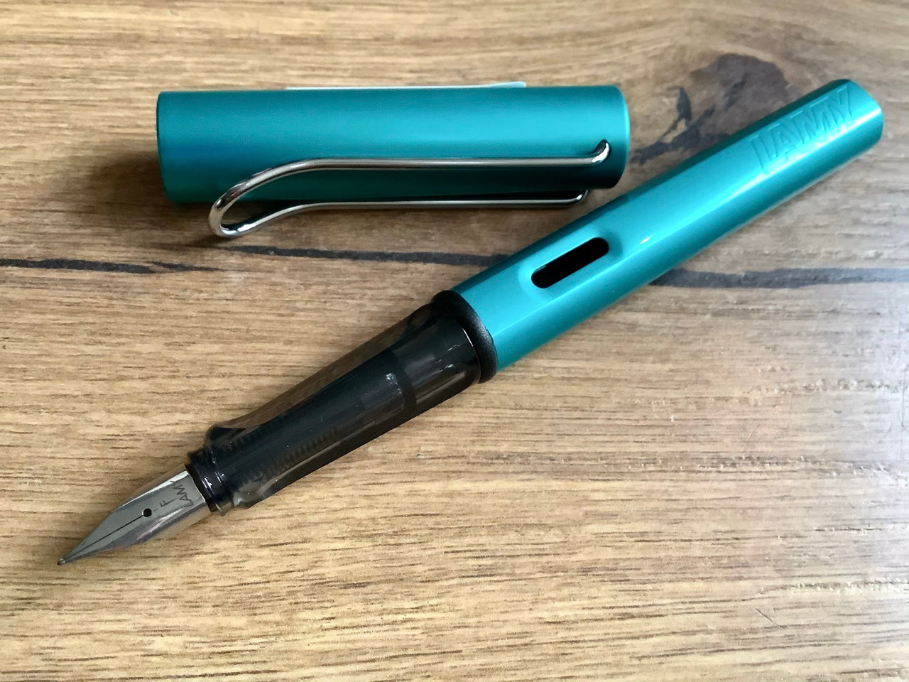 Füllhalter von LAMY aus Aluminium in türkis (Griffstück aus schwarz-transparentem Kunststoff). 
Erhältlich bei Polly Paper Schreibwaren in Berlin-Mitte