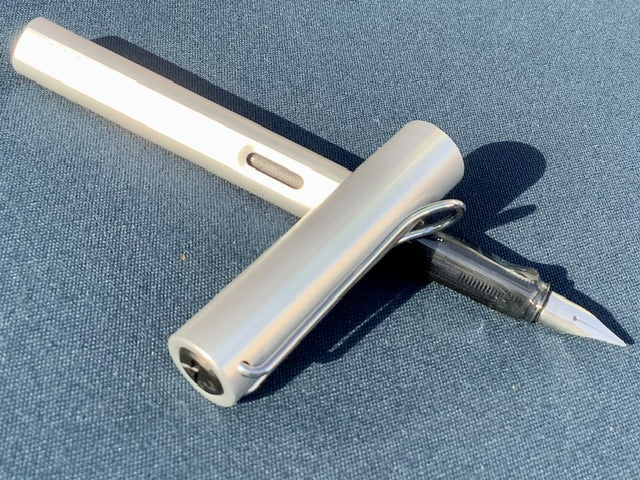 Füllhalter von LAMY aus Aluminium in hellem silber , Griffstück aus transparentem Kunststoff. 
Erhältlich bei Polly Paper Schreibwaren in Berlin-Mitte