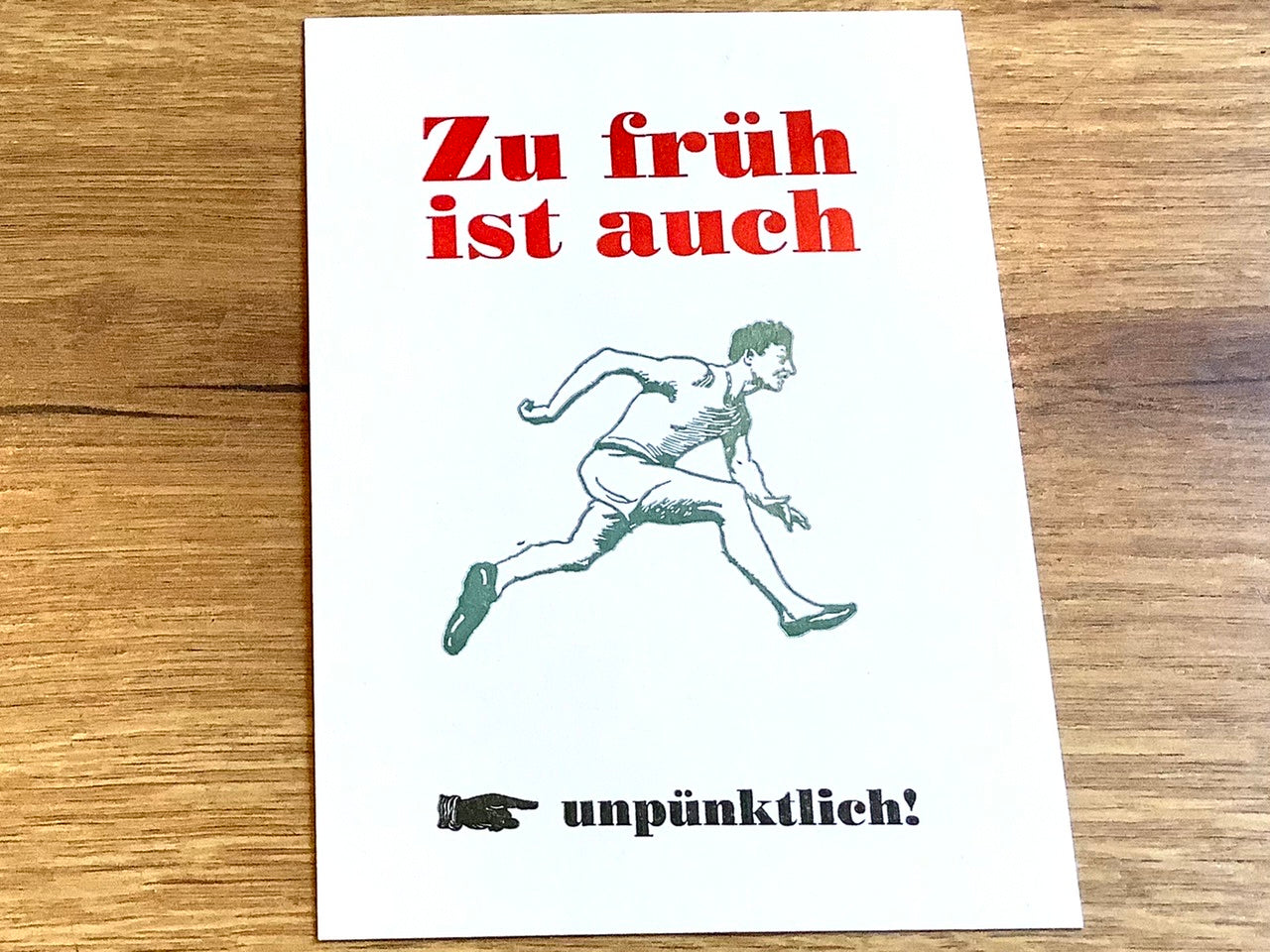 "Zu früh ist auch unpünktlich" steht auf der Postkarte, dazu ein rennender Mann